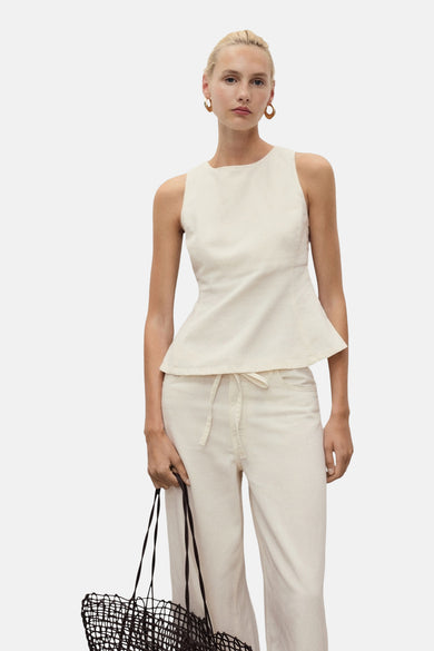 Blouse sans manches en écru de MANGO, avec une silhouette peplum, à associer avec un pantalon et des sandales.