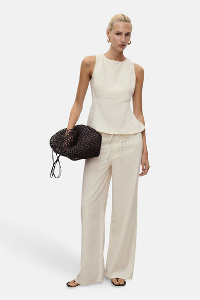 Blouse à manches courtes MANGO, couleur écru, avec une silhouette peplum et associée à un pantalon large de couleur crème et des sandales noires.