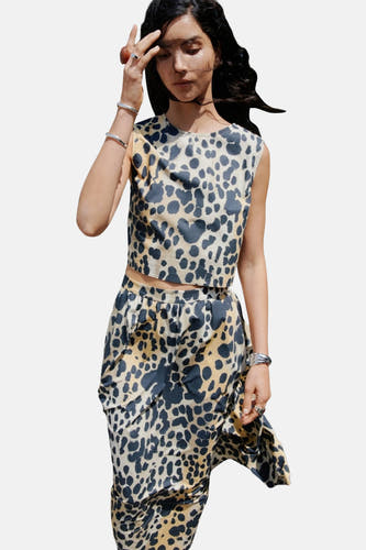 Blouse sans manches beige de MANGO à imprimé léopard, associée à une jupe coordonnée et des bracelets en argent.