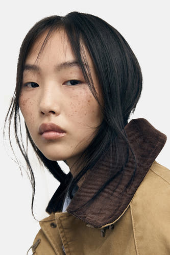 Manteau court beige de MANGO, avec un col marron et des poils lâches.