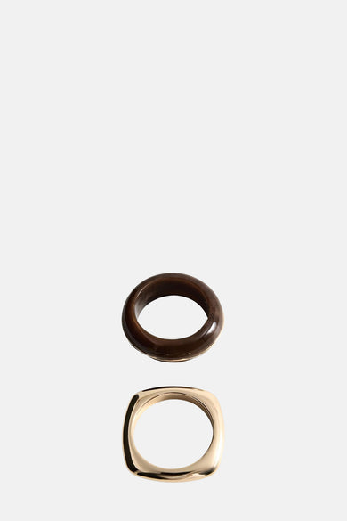 Bracelet en or de MANGO, avec un design carré arrondi, sous un bracelet marron.