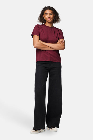 Bordeaux T-shirt met korte mouwen van PIECES®, gedragen met zwarte jeans en sneakers.