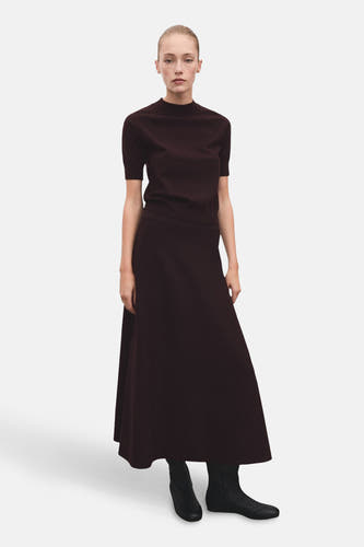 Bordeaux lange rok van MANGO, gecombineerd met een top en zwarte enkellaarsjes.
