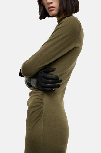 Robe khaki à longues manches de MANGO, avec des détails pliés et des gants en cuir noir.