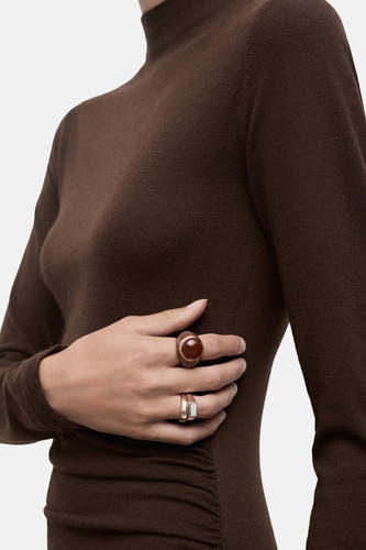 Robe brune à longues manches de MANGO, avec une coupe ajustée et des anneaux d'or.