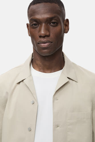Chemise beige à manches courtes de MANGO, avec col et boutonnière et poche poitrine.