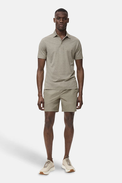 Man in polo en shorts, beige, sportieve outfit, staand.