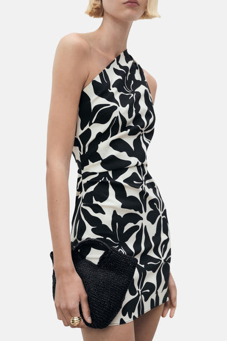 Robe sans manches noire de MANGO, avec un motif floral abstrait noir et blanc et une pochette noire.