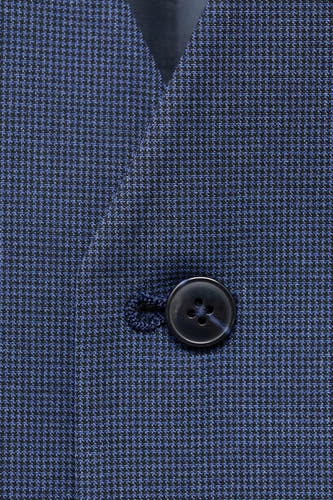 Blauw gilet van MANGO, met een subtiele pied-de-poule textuur en een enkele knoop.
