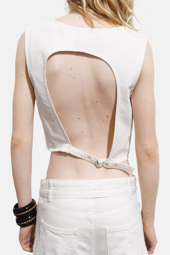 Blouse à manches longues écru de MANGO, avec dos nu et ceinture ajustable sur le dos, associée à une jupe blanche et un bracelet.