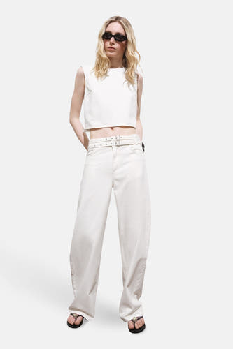 Blouse à manches longues écru de MANGO, portée avec un short blanc à cece et des chaussons noirs.