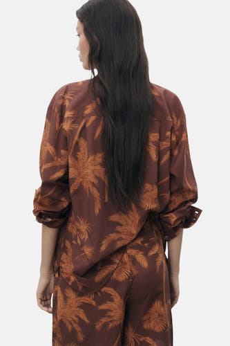 Chemise brune à longues manches de MANGO, avec un imprimé all-over de palmiers et des poignets boutonnés.