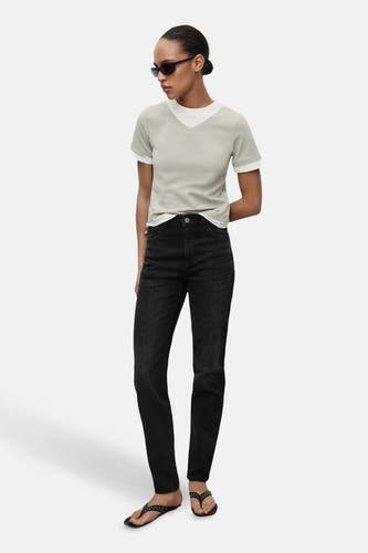 Jean mom marron clair de MANGO, associé à un T-shirt gris clair et des sandales noires avec des strass.