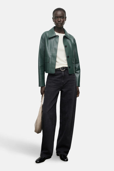 Groene korte jas van MANGO, gedragen met een witte top, zwarte broek met riem en handtas.
