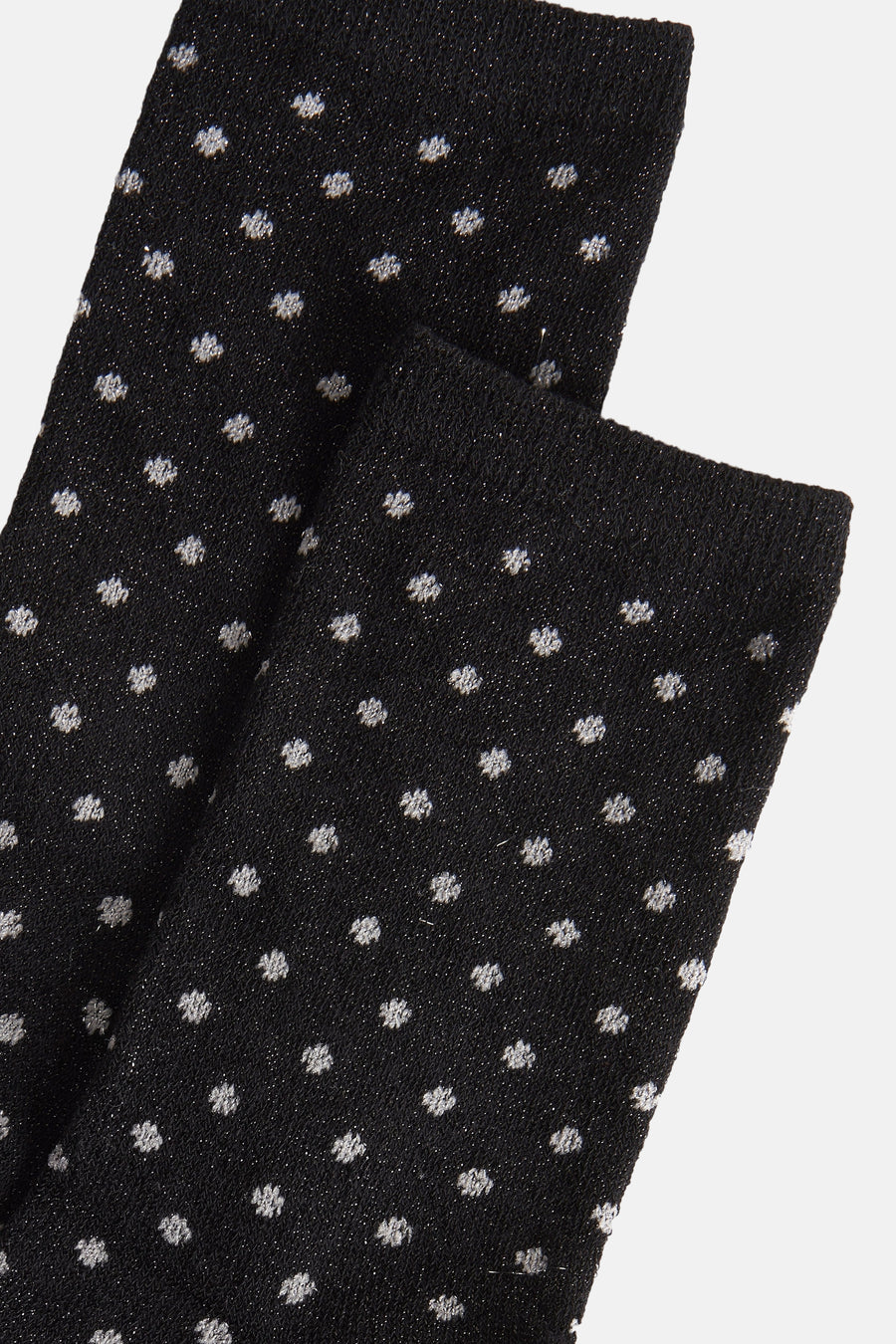 Chaussettes noires de PIECES® avec des taches brillantes sur un fond lisse, gros plan.