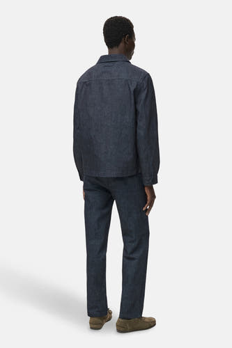 Manteau de denim bleu marine MANGO, vu de derrière, associé à des jeans noirs et des chaussures en cuir marron.