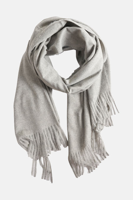 Chapeau d'hiver gris de MANGO, avec franges aux extrémités et une coupe fluide et drapée.