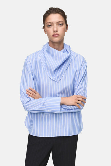 Blouse à rayures bleues avec longs manches de MANGO, avec un col distinctif et des bras croisés.