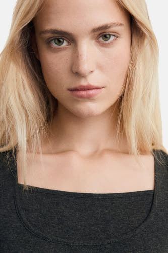 T-shirt gris à manches longues de MANGO, gros plan d'un modèle aux cheveux blonds portant une chemise gris foncé.