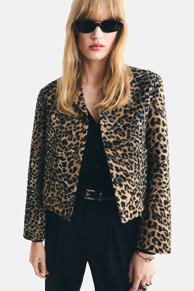 Blazer marron de MANGO avec imprimé léopard, porté avec une blouse noire, un pantalon et des lunettes de soleil.