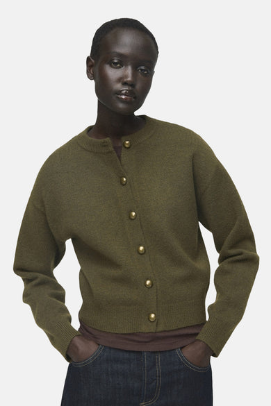 Gilet khaki de MANGO, vu d' lrière, porté sur un t-shirt marron et des jeans larges bleu marine.