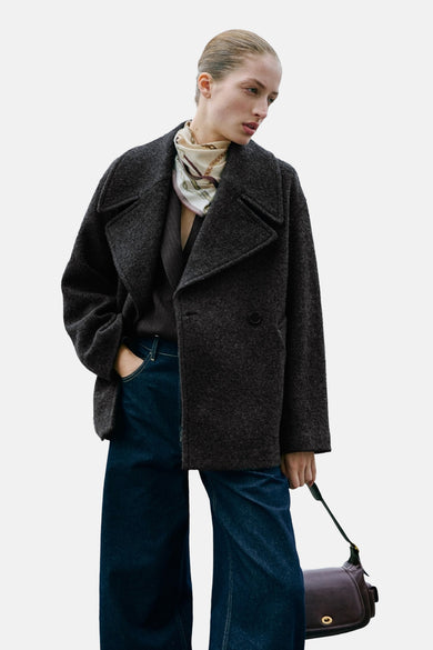 Manteau court gris de MANGO, à double boutonnage, associé à un foulard en soie et des jeans larges.