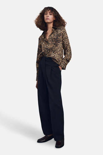Multikleurig hemd met lange mouwen van MANGO, met luipaardprint en gecombineerd met donkere, losvallende pantalon en loafers.