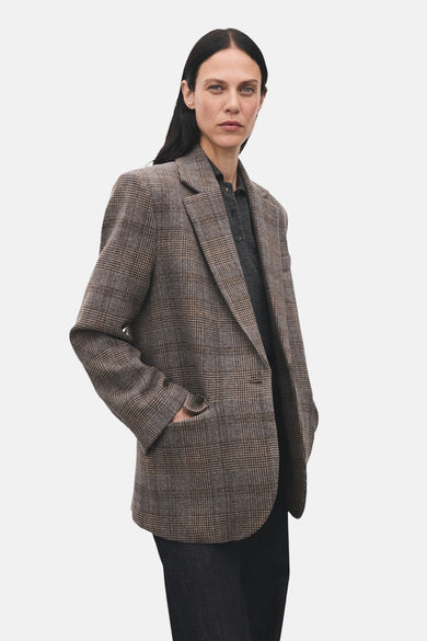 Blazer marron de MANGO avec motif à carreaux, associé à un pantalon foncé, vu de l'arrière.