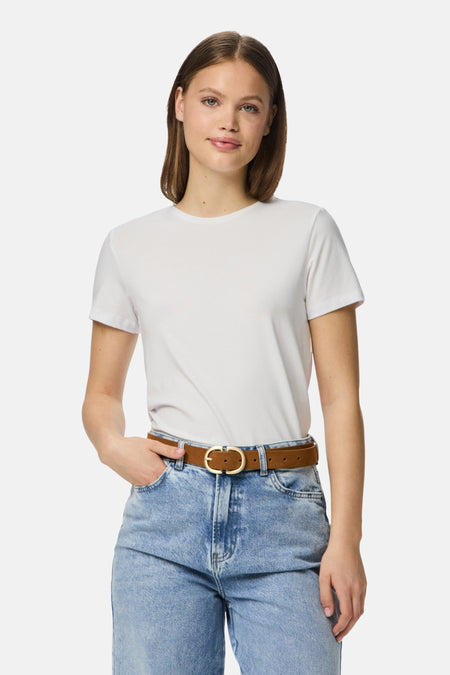 Vrouw in witte T-shirt, jeans met riem.

