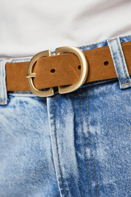 Bruine suède riem met gouden gesp, blauwe spijkerbroek.
