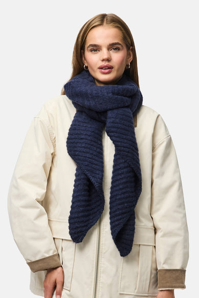 Châle d'hiver bleu de PIECES®, porté avec une veste beige à fermeture éclair et manchettes.