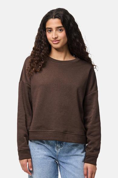 Pull marron de PIECES, porté avec un jean bleu et stylisé avec des boucles décontractées.