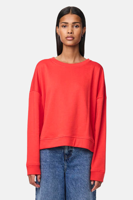 Pull-over rouge de PIECES, associé à des jeans larges et une handte noire.