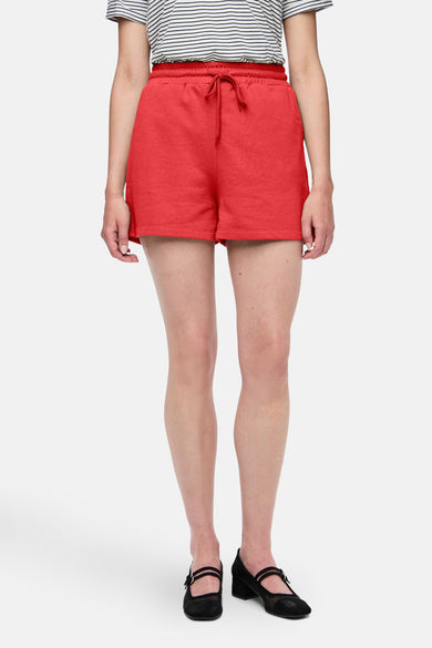 Short rouge de PIECES, avec une ceinture à la taille et porté avec un haut rayé et des chaussures noires.