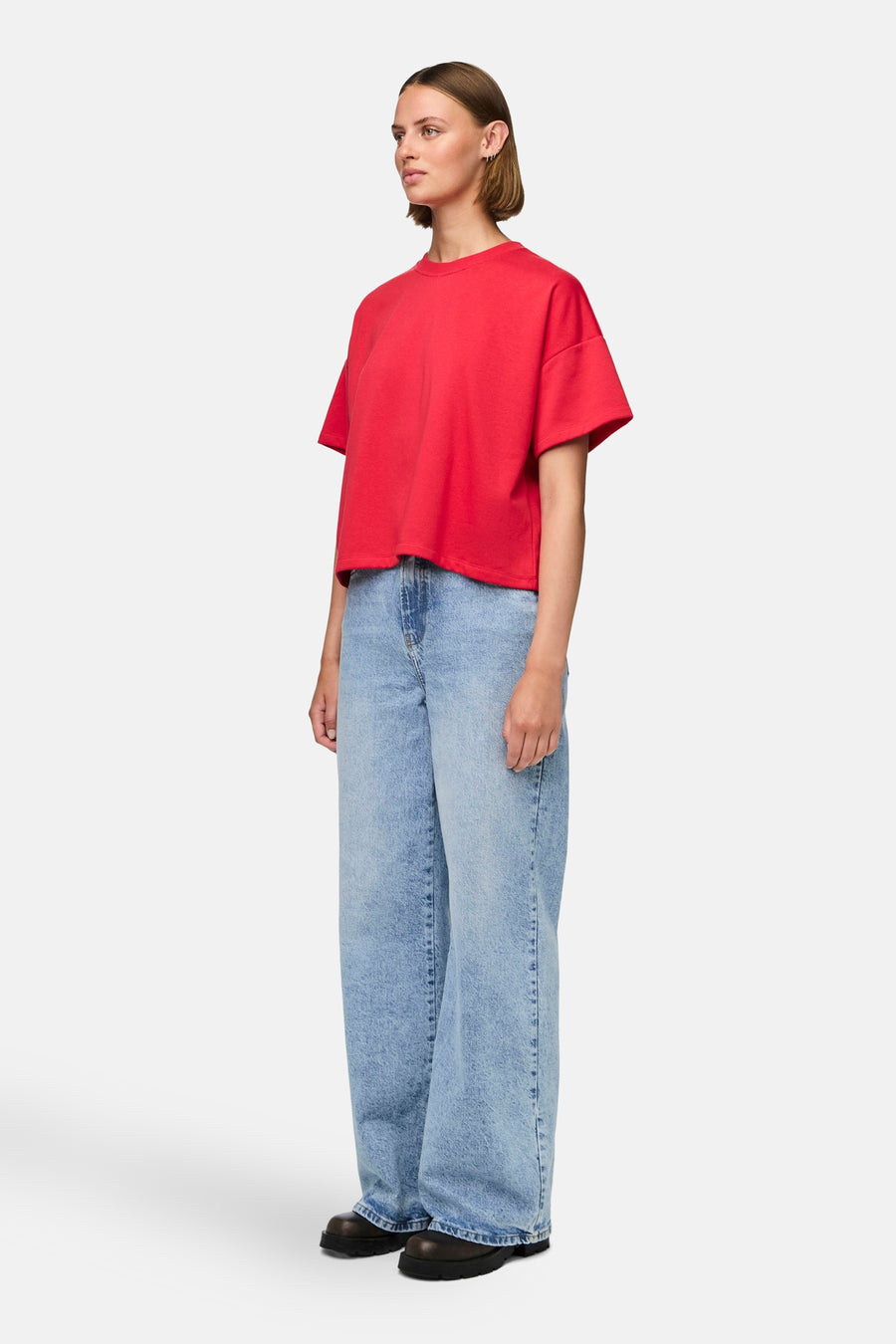 T-shirt rouge à manches courtes de PIECES®, porté avec des jeans larges et des chaussures noires, debout.