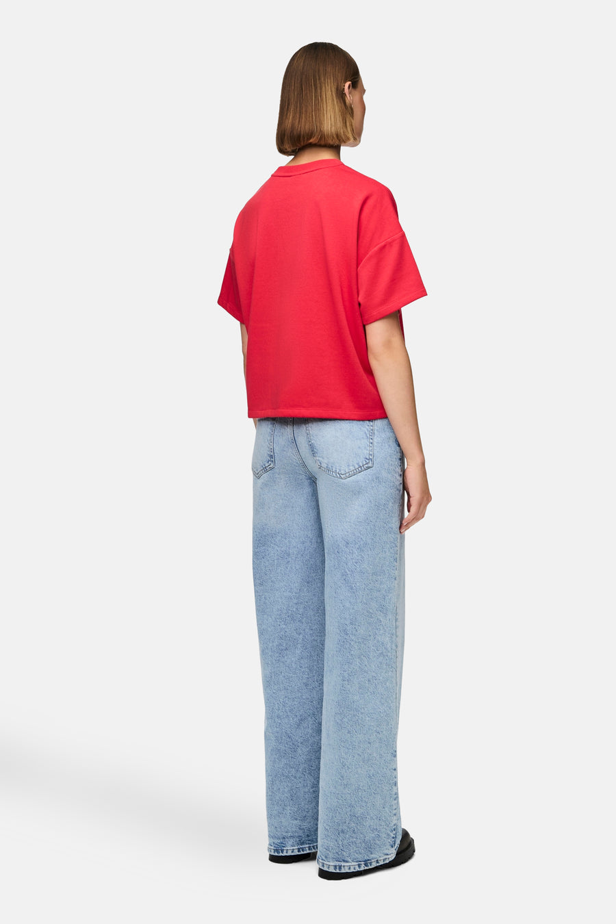 T-shirt rouge à manches courtes de PIECES, porté avec des jeans bleus larges, vu de dos.