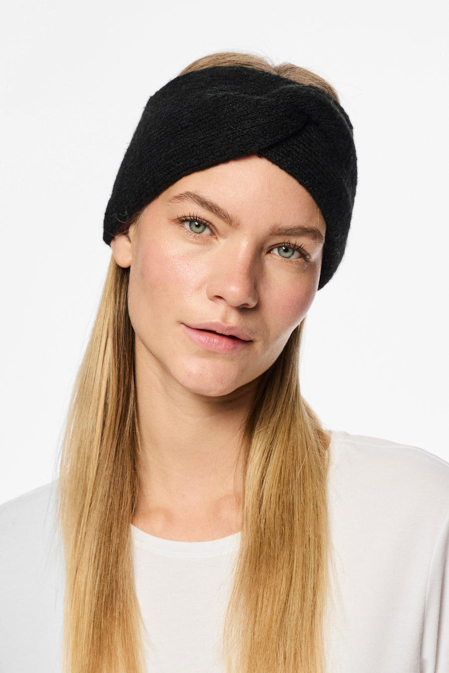 Écouteurs noirs de PIECES, avec un détail tourné à l'avant, portés par une femme aux cheveux blonds.