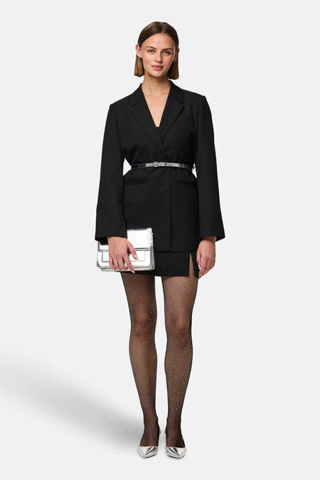 Pantys noirs de PIECES®, avec un motif en filet et des détails subtils scintillants, portés avec un blazer noir et des accessoires argentés.