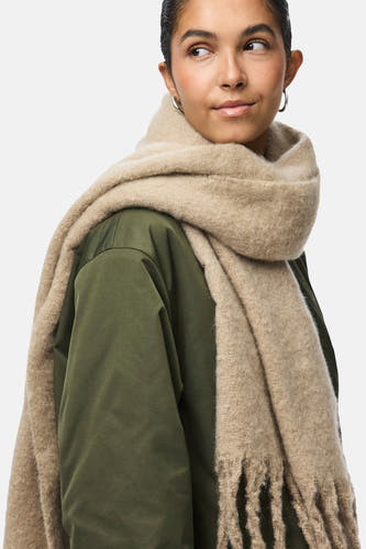 Châle d'hiver beige de PIECES, porté sur une veste kaki, avec des franges.