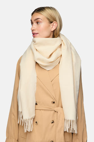 Châle d'hiver beige de Pieces avec franges, porté avec un manteau trench brun.