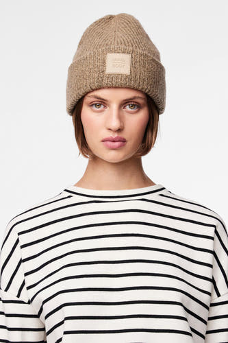 Vrouw met beige muts en gestreepte trui.