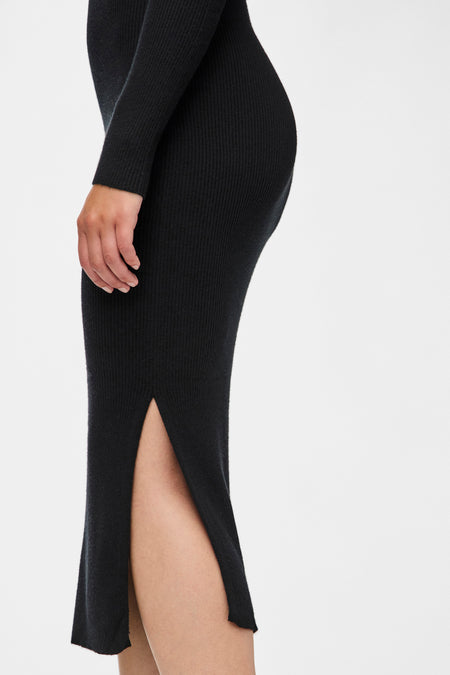 Robe noire à longues manches de PIECES®, avec texture côtelée et une haute fente, vue latérale.