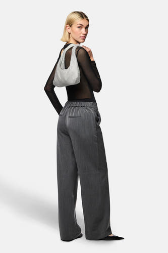 Corps noir de PIECES®, porté avec un pantalon gris et une sacoche argentée.