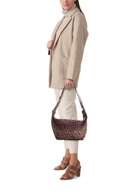 Vrouw draagt beige jas, witte broek en tas met luipaardprint.