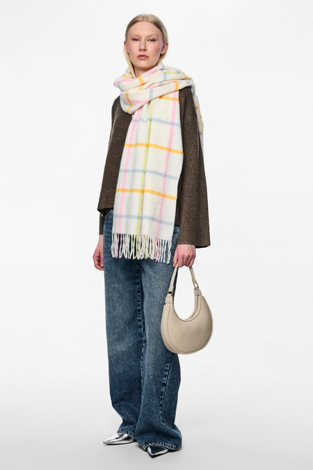 Châle d'hiver écru de PIECES® avec des lunettes pastel et des franges aux extrémités.