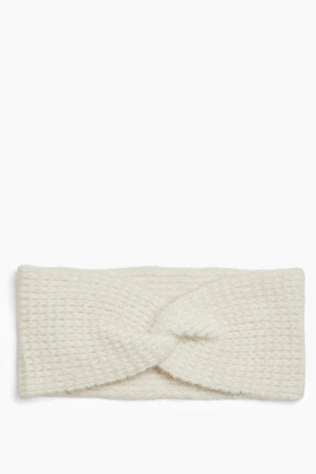 Écru oreiller de chaleur de Pieces, avec des détails boutonnés et une douce texture tricotée.
