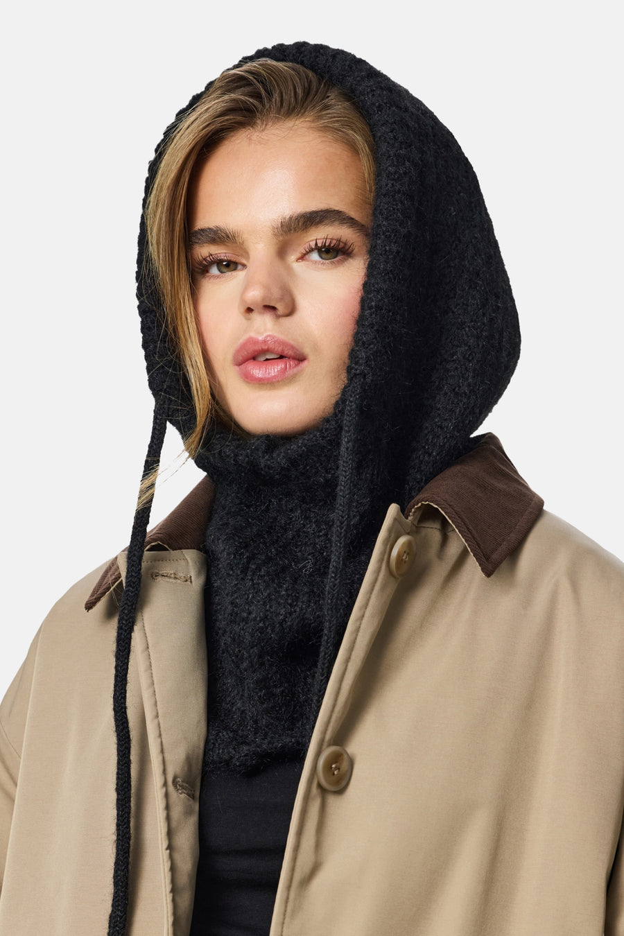 Chapeau noir de PIECES®, avec une texture épaisse tricotée et des cordons, associé à une veste beige avec un col marron.