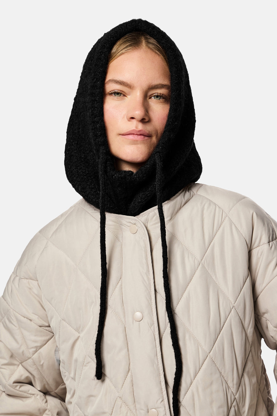 Chapeau noir de PIECES®, avec des cordons et une finition texturée, porté avec un manteau beige doublé.