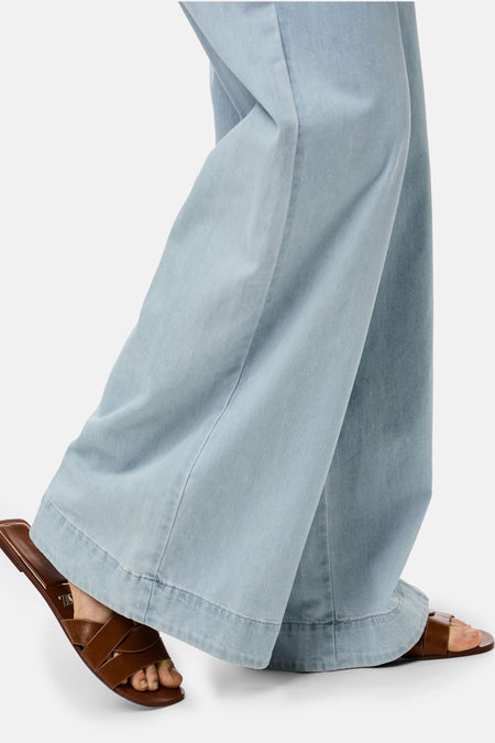 Jean bleu clair de PIECES®, avec des jambes larges et des sandales en cuir marron.