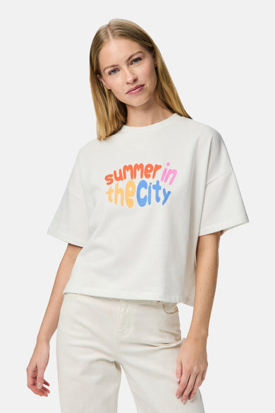 T-shirt blanc à manches courtes de PIECES®, avec une impression de texte "summer in the City" colorée, porté avec un short blanc.
